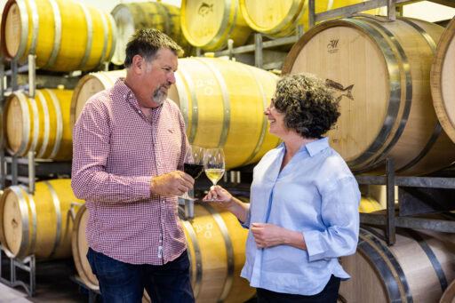 Laura & Derek clinking glasses infront of Mercurey Oak Barrels